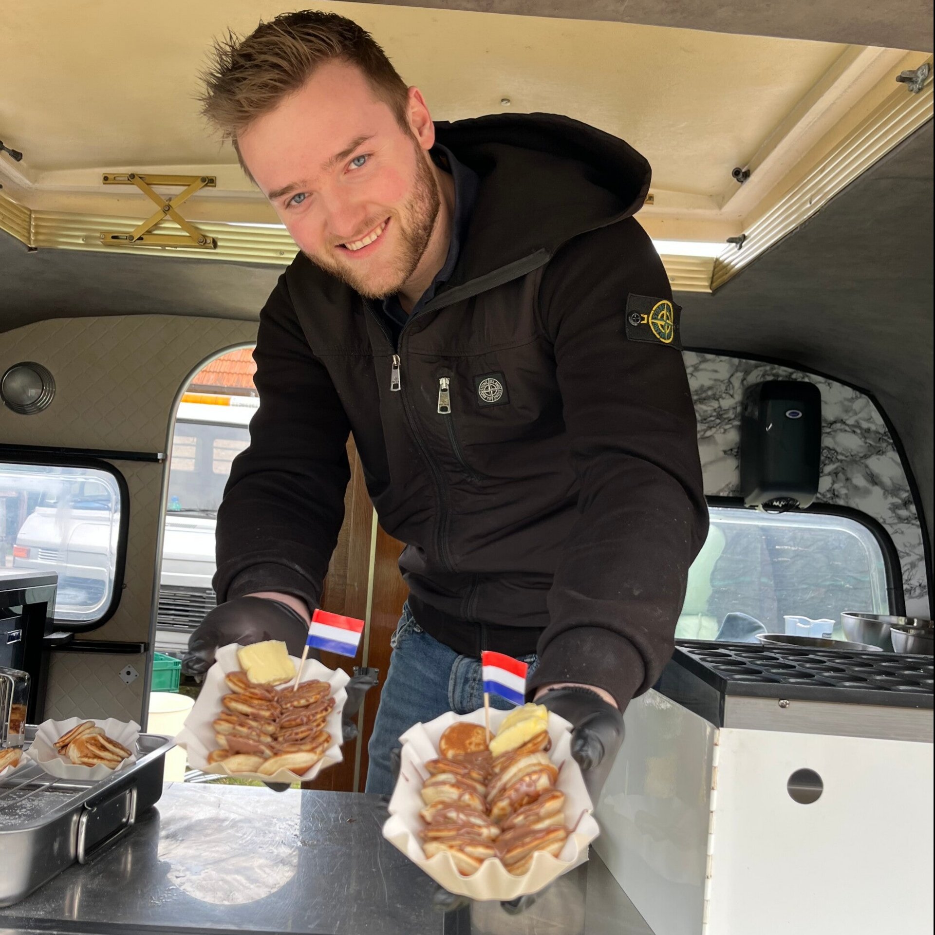 Eigenaar De Poffertjes Caravan reikt poffertjes aan